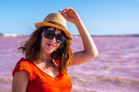 Girl enjoying the summer with red dress and straw hat in the pink lagoon of Torrevieja, Alicante. Community of Valencia. Spain, holidays in the Mediterraneanの写真素材