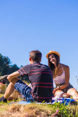 A young Caucasian couple at the picnic eating chips in the mountains by the sea enjoying the heat, summer lifestyleの写真素材
