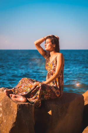 A young brunette with wet hair and a floral dress by the sea, summer llifestyle, looking leftの写真素材