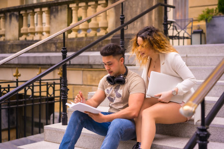 Young entrepreneur couple doing teamwork. In the city and with a computer, a boy in headphones and a...
