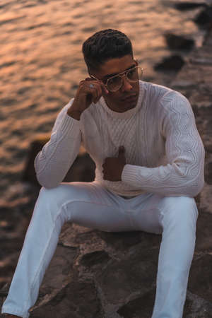 Summer lifestyle, a young Latino enjoying summer vacations. dressed in white with pants and sweater, enjoying the sunset, vertical photoの写真素材