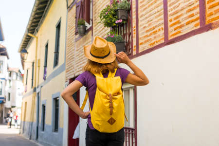 Lifestyle, an adventurous hiker with a yellow backpack visiting a traditional rural village, copy and paste space, Municipality of Ea in the Basque country. Spainの写真素材