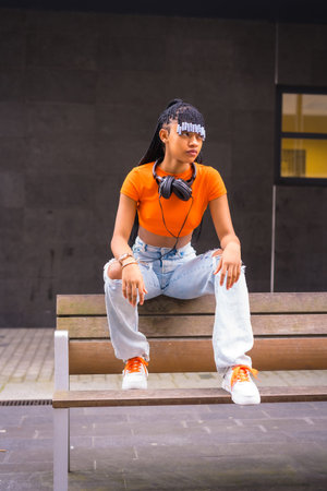 Lifestyle with a young trap dancer in the city. Black grind girl of African ethnic group with orange...
