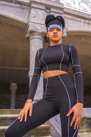 Black ethnic girl with braids with with black full body suit. I posed on some stairs next to the...