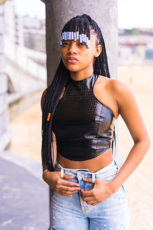 Black ethnic girl with braids with leather top and cowboy pants. Enjoying the summer holidays next...
