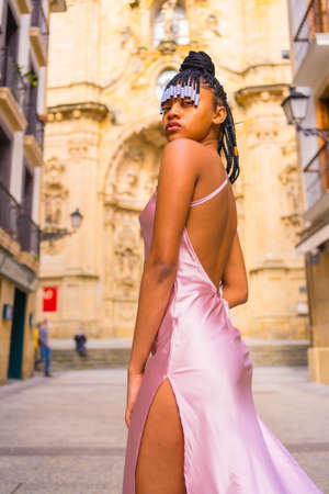 Dominican ethnic girl with braids with a beautiful pink dress. Fashion enjoying the summer in a beautiful church of the city, seductive lookの写真素材