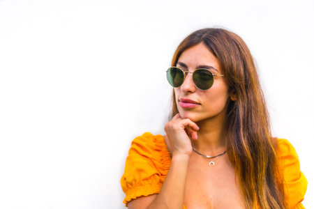 Lifestyle of a young caucasian brunette with orange t-shirt, sunglasses and short pants on a white...