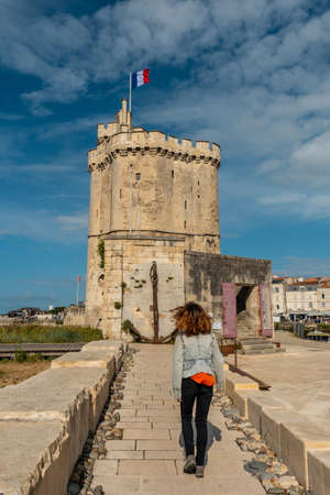 A young woman on vacation next to Saint Nicolas Tower of La Rochelle. Coastal town in southwestern Franceのeditorial素材