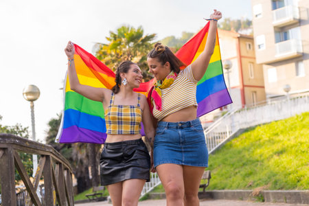 A closeup shot of two young Caucasian females holding high LGBT pride flag outdoors