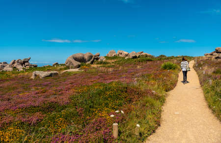 A young woman on the footpath along Lighthouse Mean Ruz, port of Ploumanach, in the town of Perros-Guirec in the Cotes-d'Armor department, in French Brittany, France.の写真素材
