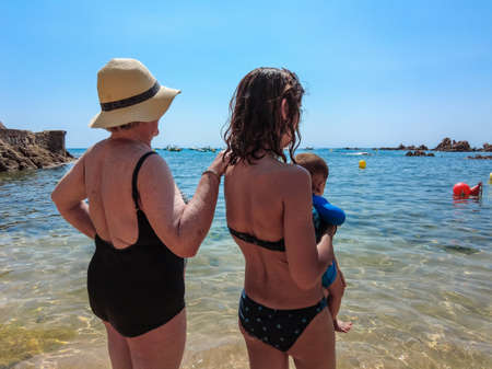 A family with their baby enjoying the summer in Cala Canyet next to the town of Tossa de Mar. Girona, Costa Brava in the Mediterraneanの写真素材