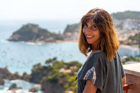 A young tourist looking at Tossa de Mar from the viewpoint in the summer, Girona on the Costa Brava of Catalonia in the Mediterraneanの写真素材