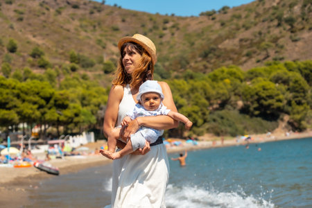 Mother with her baby on summer holidays in Cala Montjoi, beach of the Cap Creus Natural Park, Gerona, Costa Brava of Catalonia in the Mediterranean. Spainの写真素材