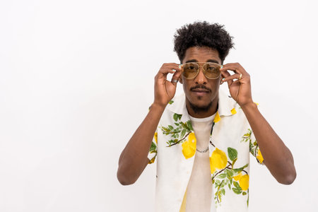 A young Cuban man with a floral shirt and glasses smiling on a white background, copy and paste...