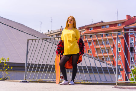 Skateboarder woman with a yellow shirt, red plaid shirt and sunglasses, in a pose with skateboardingの写真素材