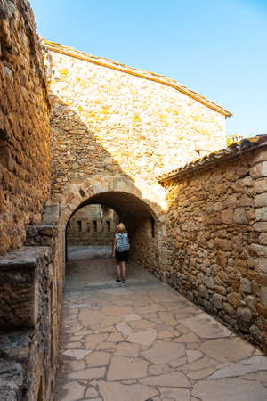 A young woman walking in Pals medieval village, streets of the historic center at sunset, Girona on the Costa Brava of Catalonia in the Mediterraneanのeditorial素材