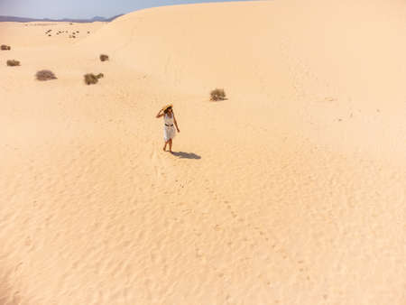 A young woman walking through the sand in the dunes of the Corralejo Natural Park, Fuerteventura, Canary Islands. Spainの写真素材
