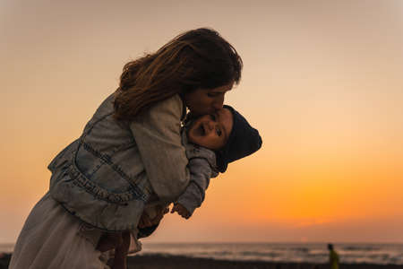 A young mother kissing her son at the Toston Lighthouse Sunset, Punta Ballena near the town of El Cotillo, Fuerteventura island, Canary Islands. Spainの写真素材