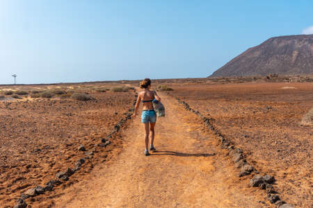 A young tourist girl walking the trails of Isla de Lobos, along the north coast of the island of Fuerteventura, Canary Islands. Spainの写真素材