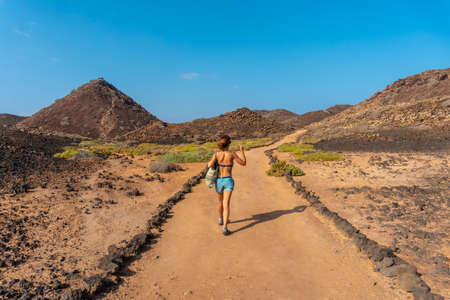 A young woman with a blue bikini on the trail to the north of the Isla de Lobos, next to the north coast of the island of Fuerteventura, Canary Islands. Spainの写真素材