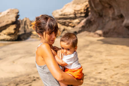A young woman with her baby by the sea in Playa de Garcey, west coast of Fuerteventura, Canary Islands. Spainの写真素材