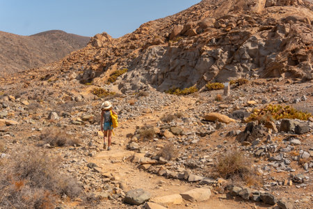 A young woman walking along the canyon path towards the Mirador de la PeÃ±itas, west coast of the island of Fuerteventura, Canary Islands. Spainの写真素材