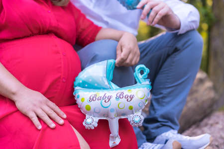 Two unrecognizable people with a baby carriage just before giving birth, pregnant session in a forestの写真素材