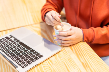 Alternative unrecognizable person with a coffee surfing the internet on the computerの写真素材