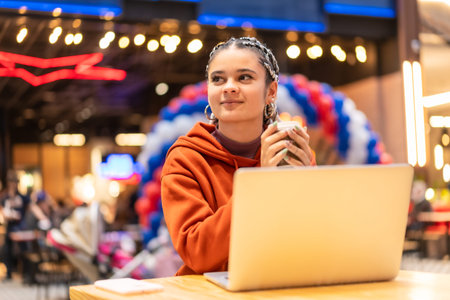 Alternative girl with white braids using a computer in a shopping center, sending an email