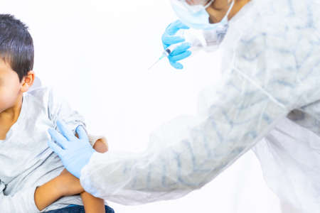 Child getting vaccine injection. Vaccination of children. Immunization in the coronavirus pandemic, covid-19, a new normal for schoolsの写真素材
