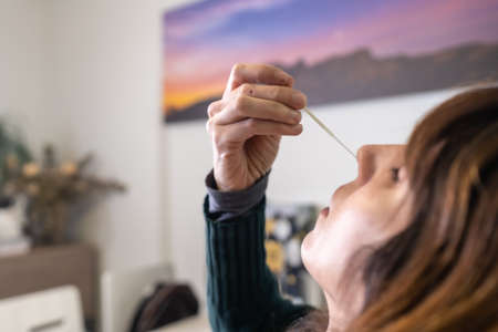 Detail of the nasal self test at your home. A young woman doing the rapid antigen test, sars-cov-2 tests. Security measures in the coronavirus pandemic, covid-19の写真素材