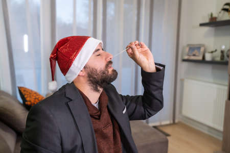 Introducing the test stick in your living room to go to Christmas dinner. Man doing the rapid antigen test at his home, sars-cov-2, coronavirus, covid-19の写真素材