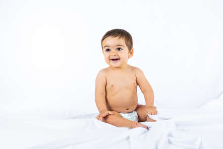 Baby boy in a studio with a white background, eight month old Caucasian newborn sitting on a clothの写真素材