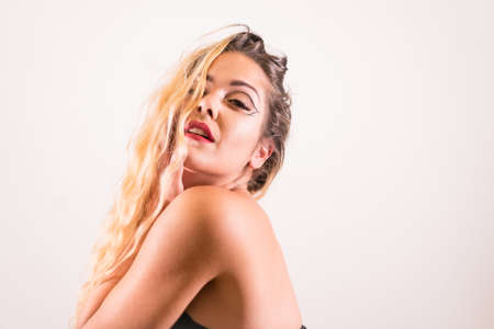 Seductive look of a Caucasian blonde girl with makeup, groomed eyelashes and with a white background, copy pasteの写真素材