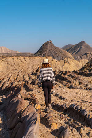 A young hiker girl with a hat visiting the landscapes of Colas de Dragon in the desert of Tabernas, AlmerÃ­a province, Andalusia. Trekking in the desert, lifestyleの写真素材