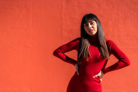 Posed brunette girl with a dress in spring, enjoying a sunny morning. Caucasian pretty a red background, copy space and pasteの写真素材