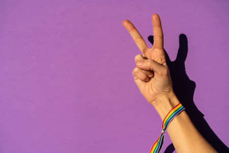 Hand of a woman with victory symbol in favor of feminism, purple background, fighting in favor of women, Female strength, LGTB flagの写真素材