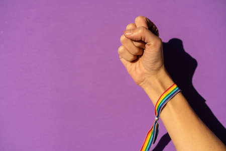 Hand of a woman with fist closed in feminism symbol in favor of feminism, purple background, fighting in favor of women, Female strength, LGTB flagの写真素材