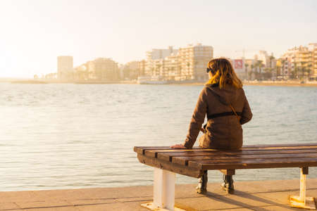 A young tourist girl at sunset on Playa del Cura in the coastal town of Torrevieja, Alicante, Valencian Community. Spain, Mediterranean Sea on the Costa Blancaの写真素材