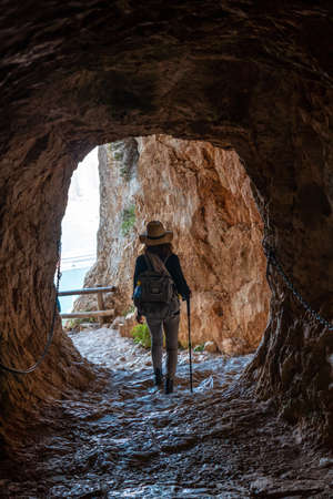 A young hiker in the tunnel of the trail in the Penon de Ifach Natural Park with the city of Calpe in the background, Valencia. Spain. Mediterranean sea. View of La Fossa beachの写真素材