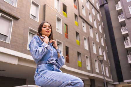 Young caucasian girl with a monkey cowboy and a black bag. Enjoying the city on vacation, lifestyle of a young girl on walking some green color house, photo from belowの写真素材
