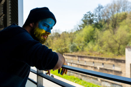 Stop war, conflict between Ukraine and Russia. Portrait of a young man with his face painted in the...