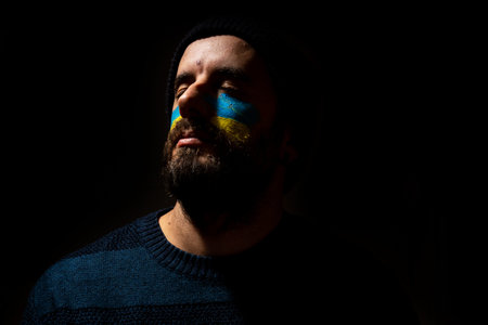 Stop war, conflict between Ukraine and Russia. A young Ukrainian with his face painted in the colors...