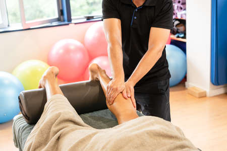 Detail of the therapeutic massage on the ball of the leg and sports recovery osteopathy. Sportsman receiving a massage by a physiotherapist on a stretcherの写真素材