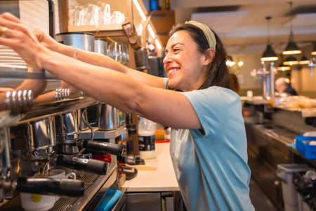 Owner of the female cafeteria preparing coffee in a coffee machineの写真素材