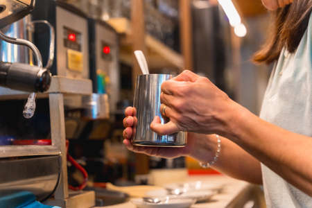 Unrecognizable waitress in the female cafeteria preparing coffee in a coffee machineの写真素材