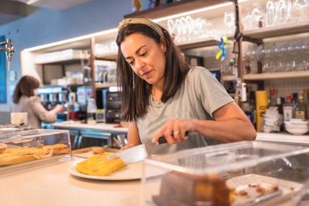 Female cafe owner cutting a snack for the customer to take with the latte