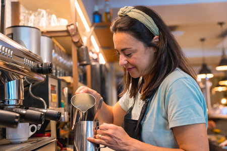 Smiling waitress in the cafeteria preparing the coffee in the coffee machineの写真素材
