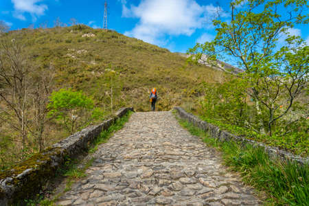 A young woman walking across the bridge on the trail between El Tornin a la Olla de San Vicente, near Cangas de Onis. Asturias. Spainの写真素材