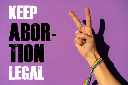 A woman with the symbol of victory or peace with a text in favor of the legalization of abortion. Protest not to make abortion illegal in the united states, pro-choice, pro-life, on a purple backgroundの写真素材